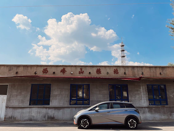 A sleek car from Bundelkhand Car Rental parked in front of a historic Jhansi landmark under a clear blue sky.