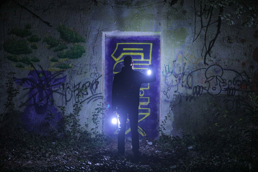 a person standing in a tunnel with graffiti on the walls