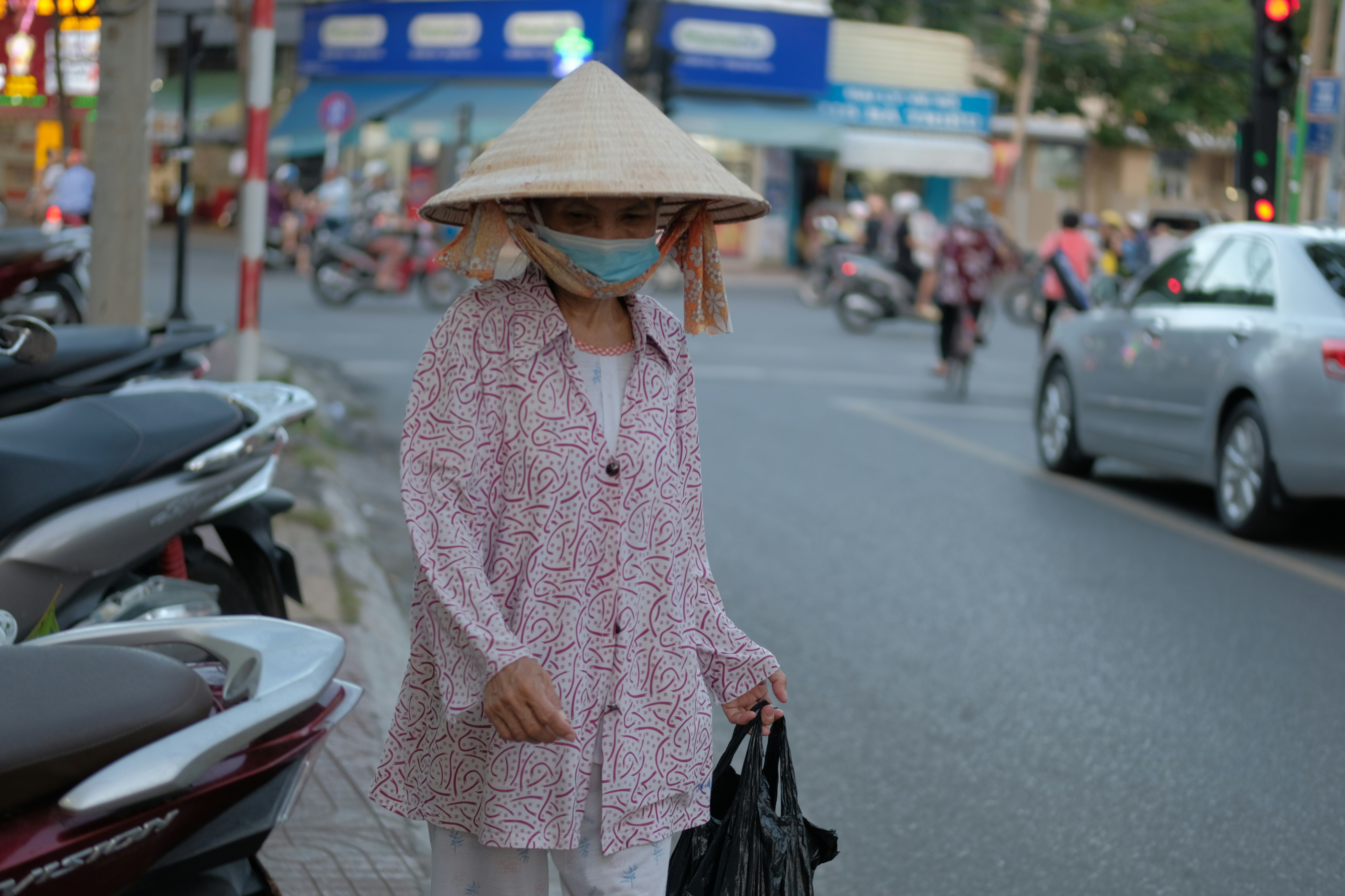 a woman in a pink dress and hat walking down a street