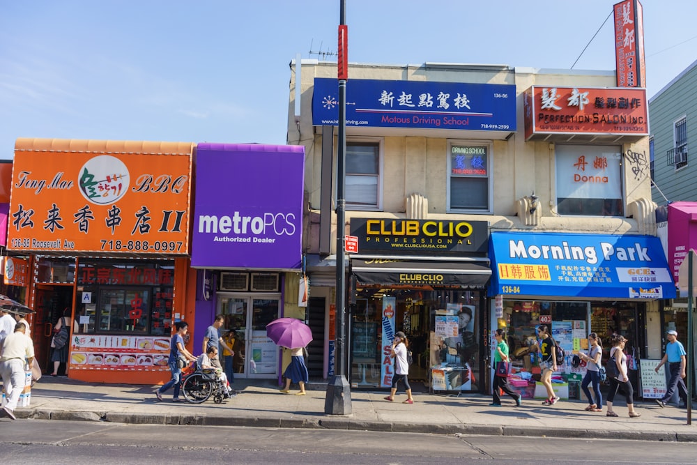 a group of people walking on the sidewalk in front of a store