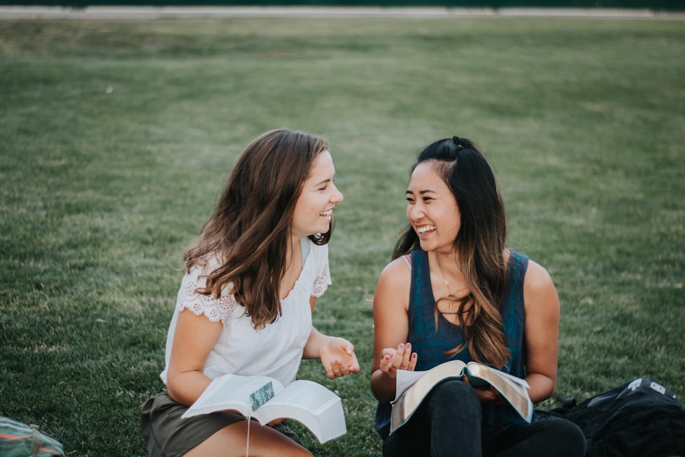 a couple of women sitting on the grass