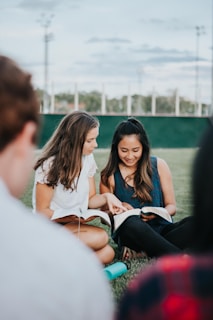 a group of people sitting on the ground looking at a book