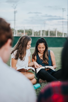 a group of people sitting on the ground looking at a book