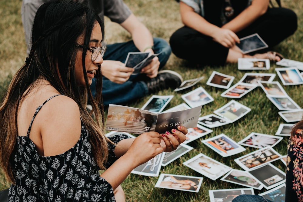 a group of people sitting on the grass playing cards