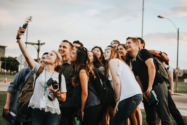 A group of friends taking selfies at an outdoor event.