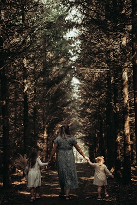 a person and two children walking through a forest