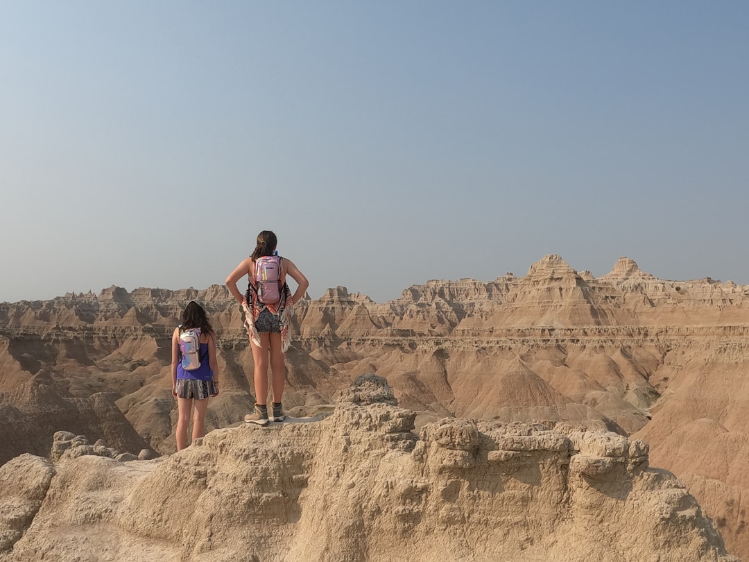 two people standing on a rock,