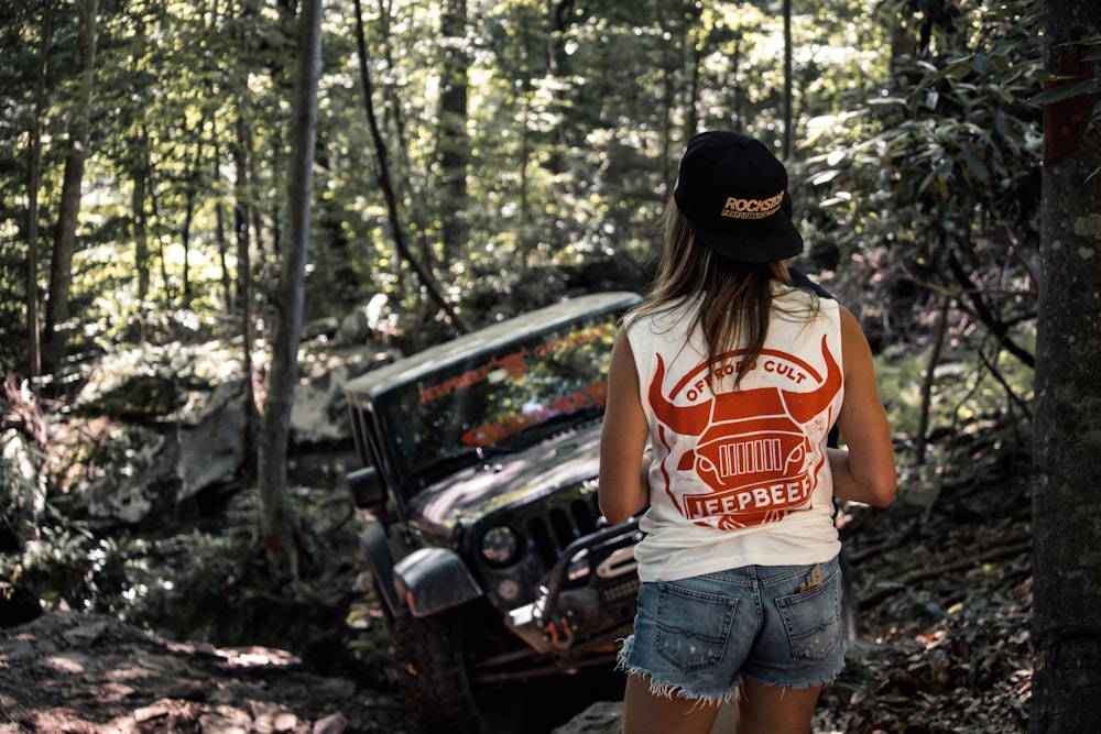 a woman standing next to a car in the woods