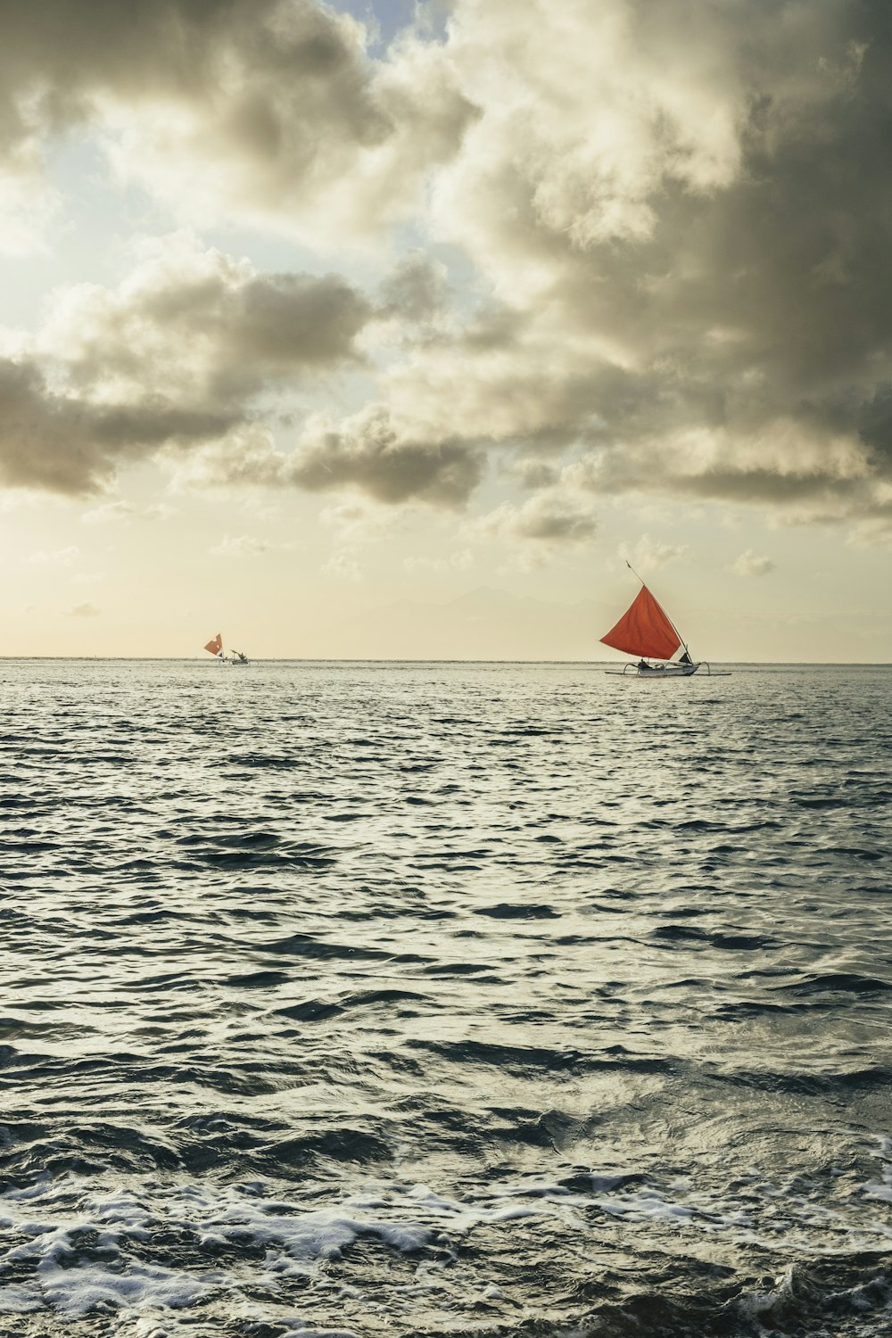 a group of sailboats on the water under a cloudy sky