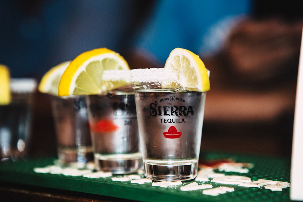 a group of glasses with lemons and a slice of lemon