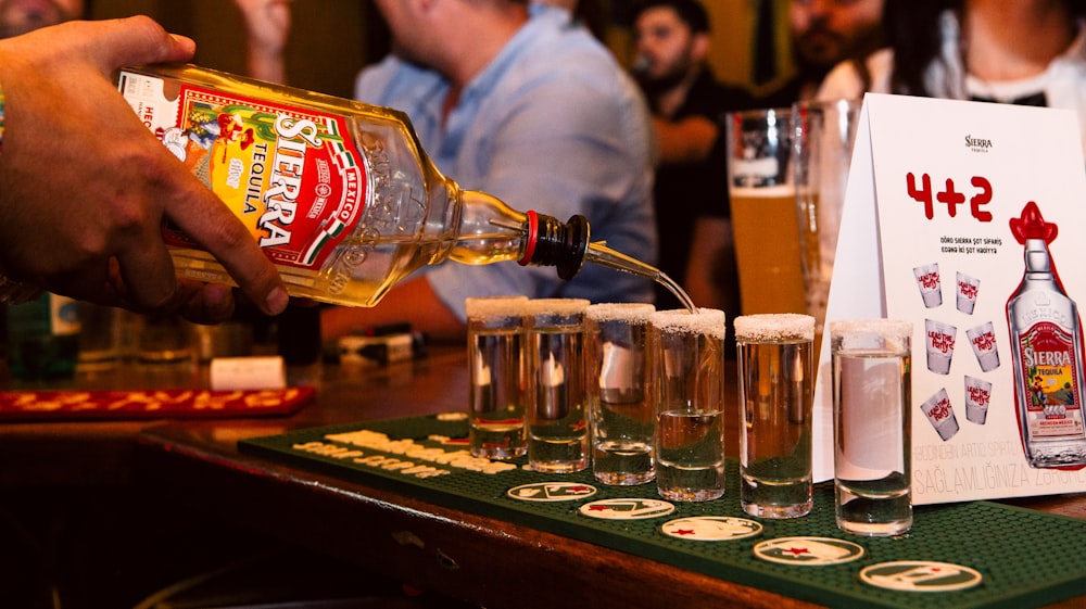 a person pouring a drink into a glass