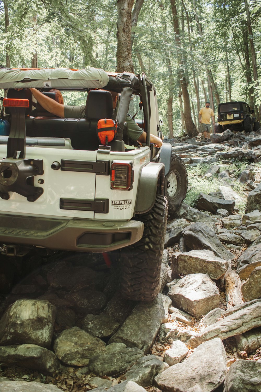 a vehicle with a flatbed on rocks in the woods