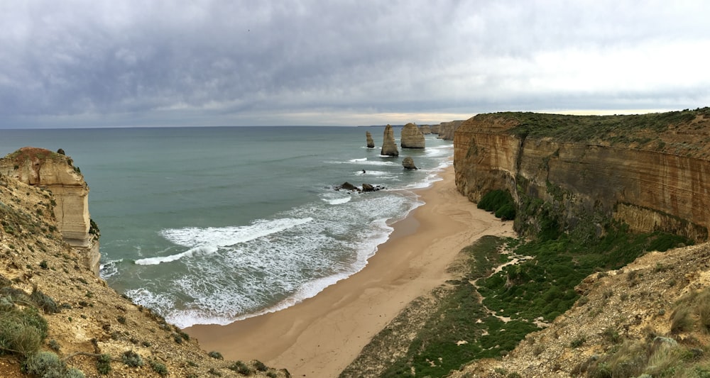 a beach with a cliff and a body of water