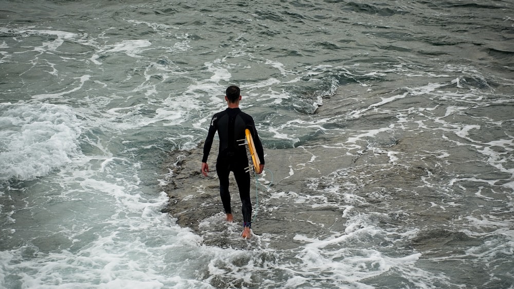 a man carrying a surfboard in the ocean
