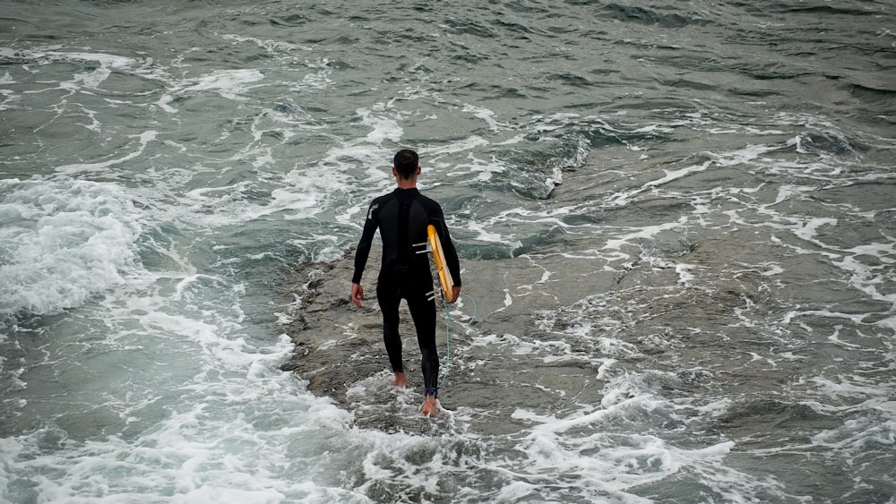 Ein Mann trägt ein Surfbrett im Ozean