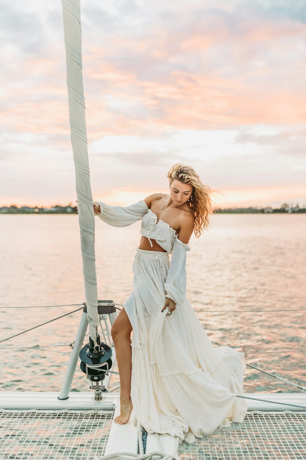 a person in a white dress leaning against a pole on a boat