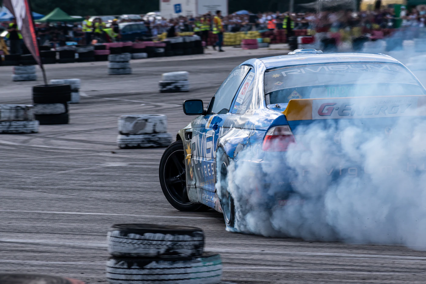 Drift car producing rear tire smoke during a closed-course drift event