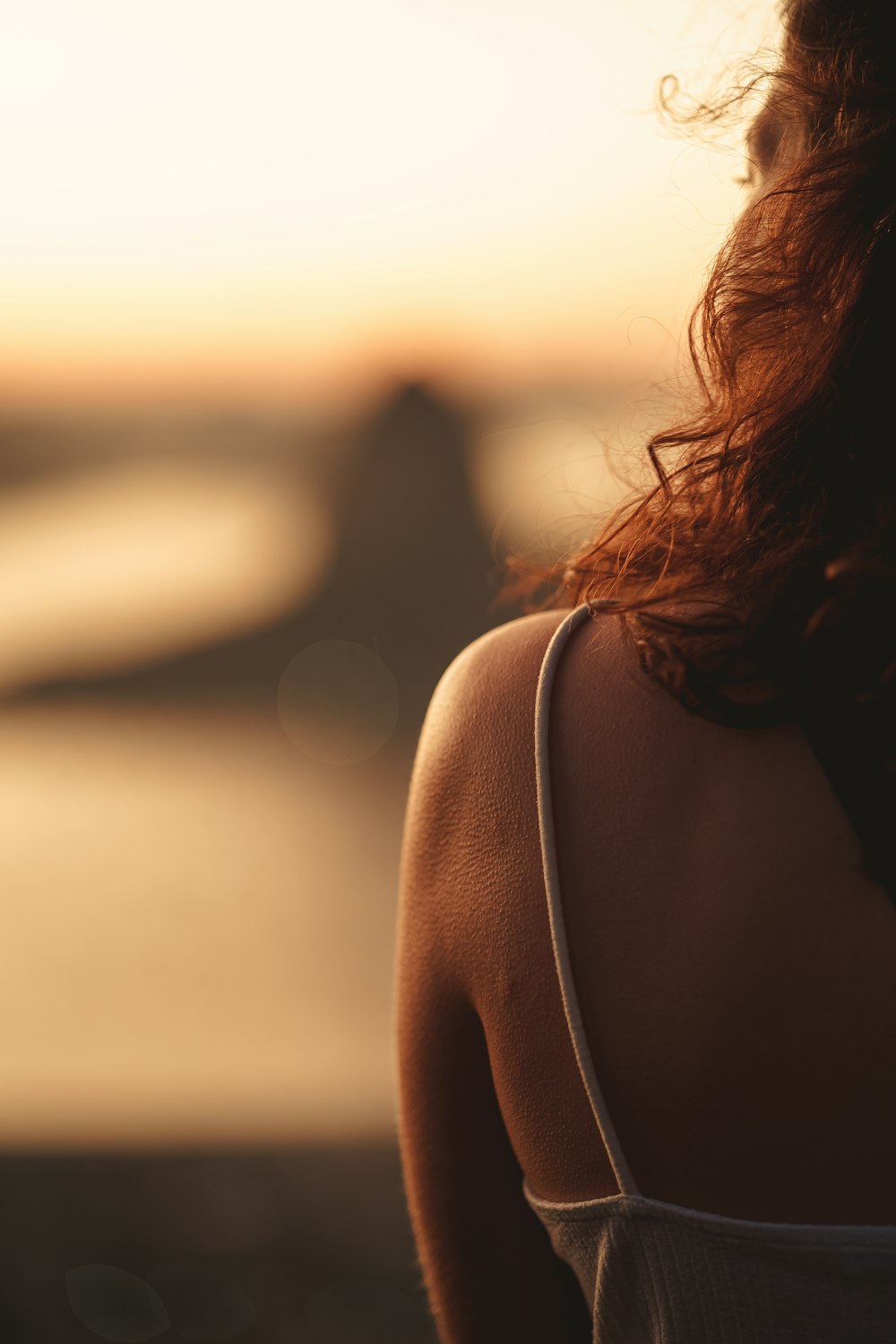 a woman's back with a sunset in the background