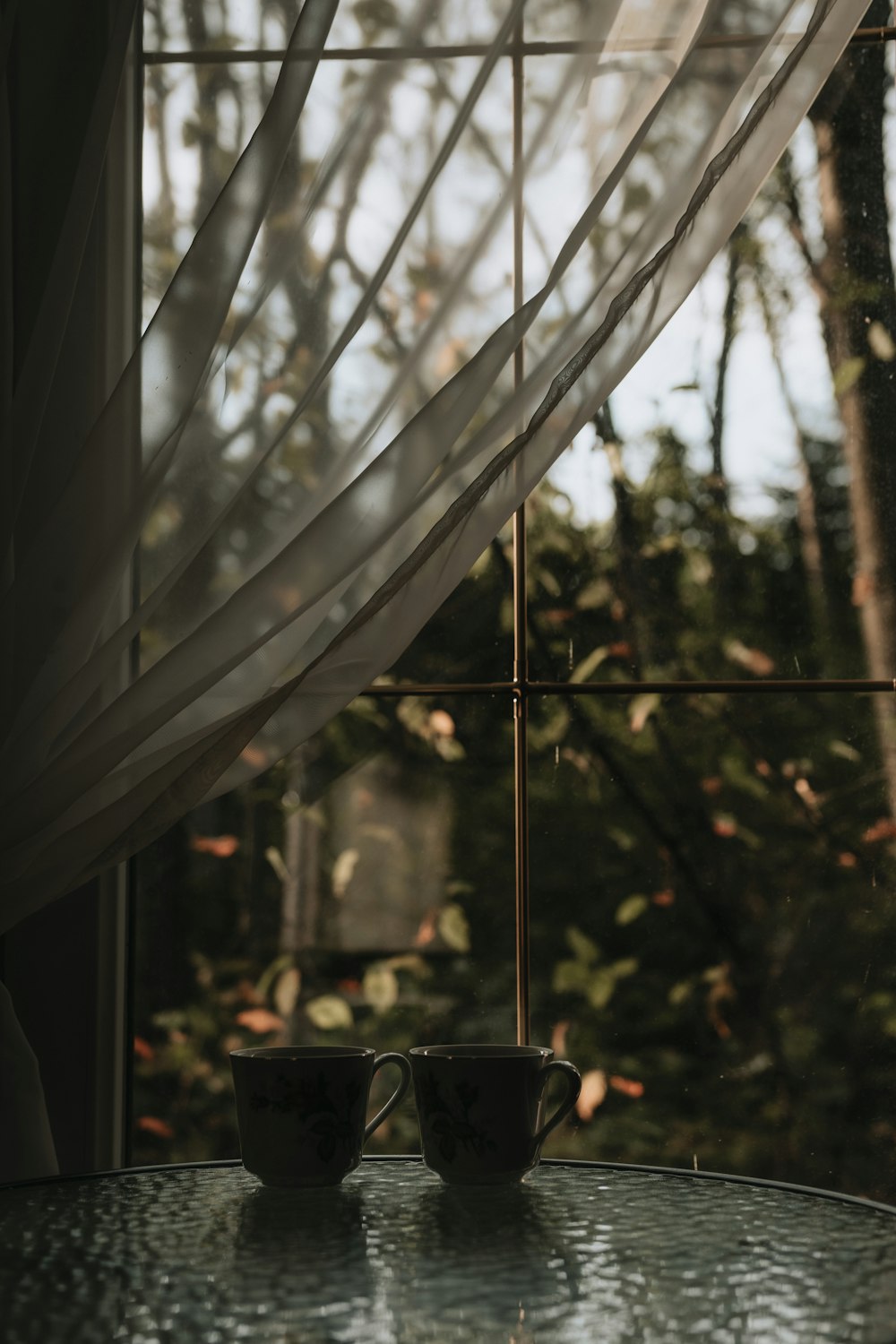 a couple of mugs on a table under a window