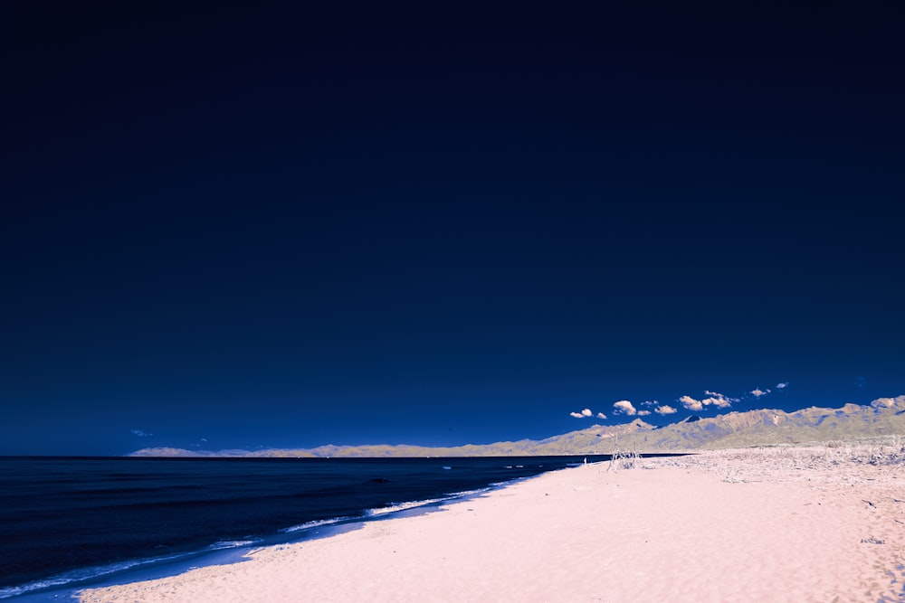 a beach with a body of water and a blue sky