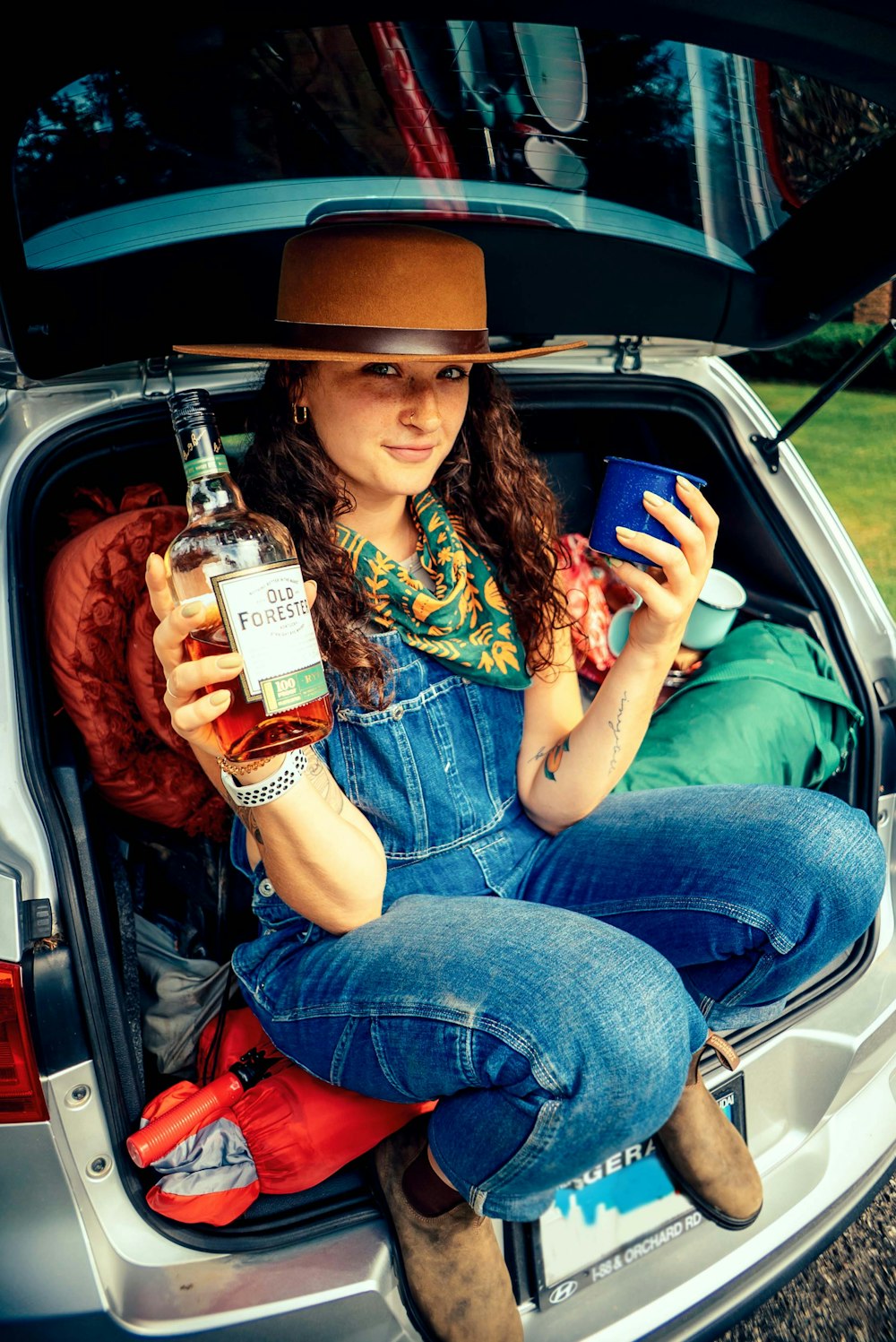 a woman sitting in a car holding a bottle of beer