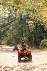 A rider wearing a helmet speeding through a forest trail on an ATV.