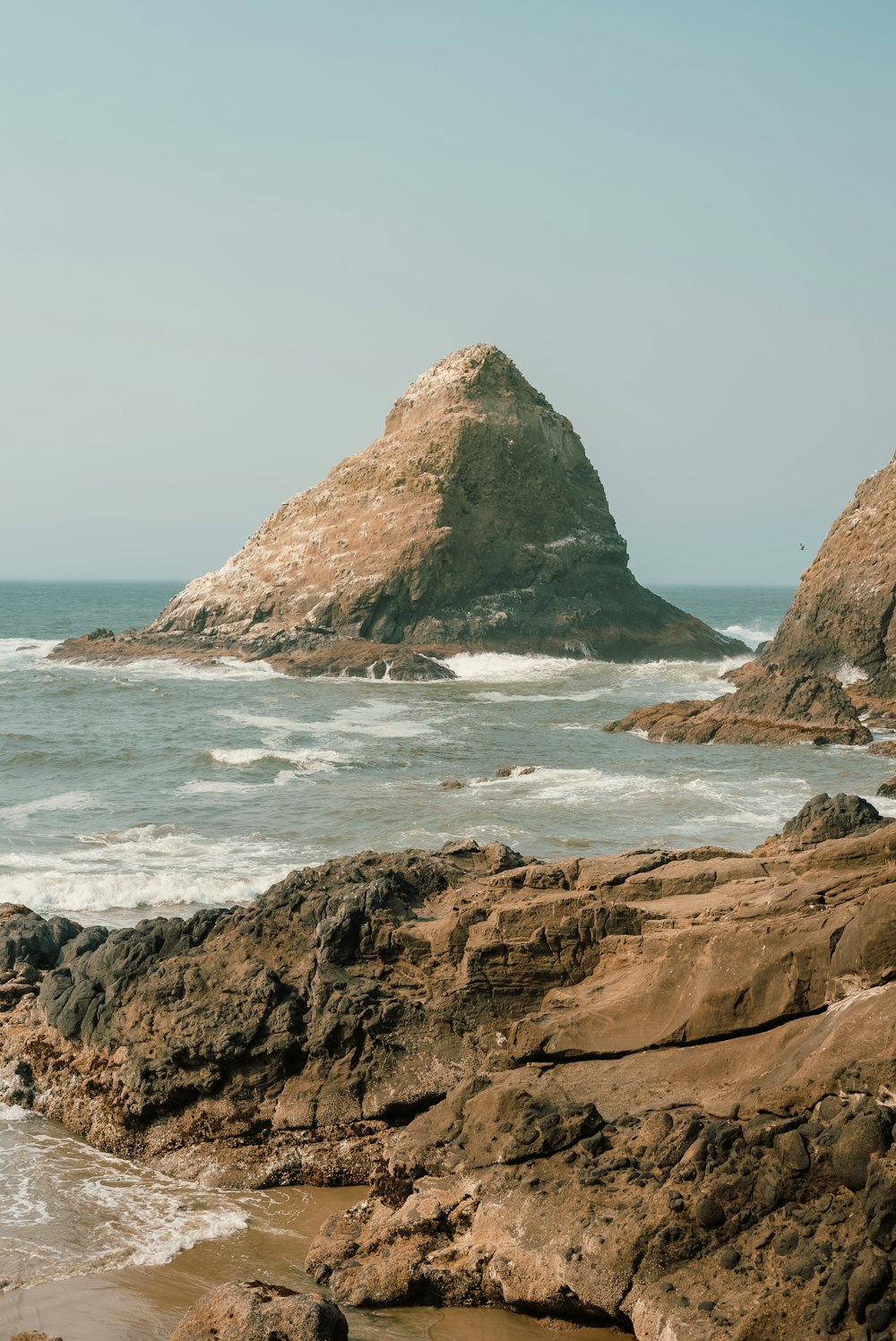 真ん中に大きな岩があり、カボデラベラを背景にした岩だらけのビーチ