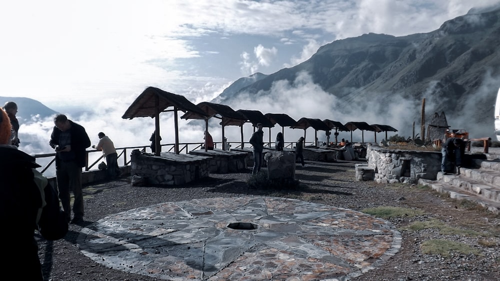 a group of people standing around a stone structure with umbrellas