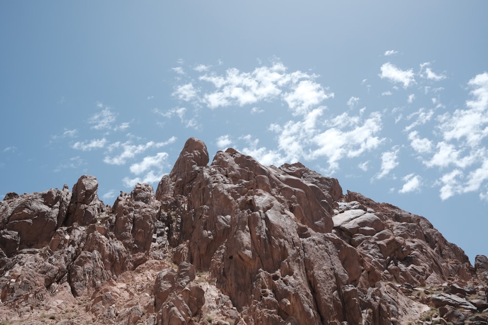 a rocky mountain with blue sky and clouds