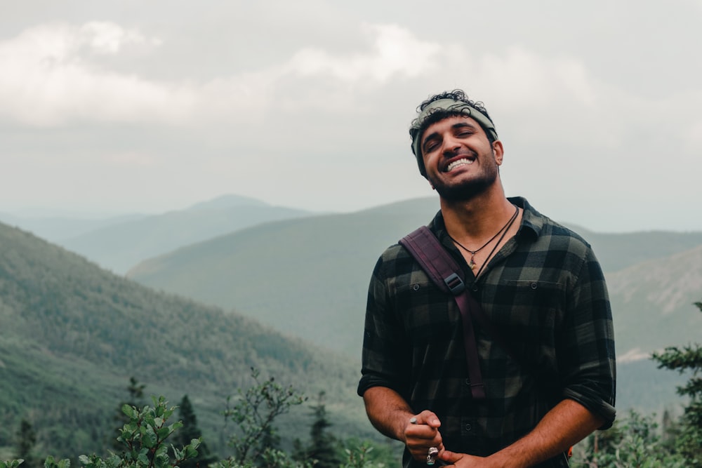 a man smiling with mountains in the background