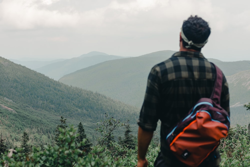 a man with a backpack looking at a valley