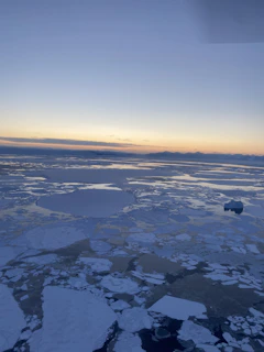 A serene arctic landscape with a glowing sunset reflecting off melting icebergs.