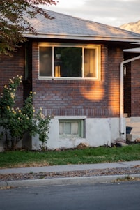 A bright, clear storefront window next to a cozy house with gleaming windows on a sunny day.