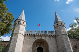 a stone castle with a flag on top with Topkapı Palace in the background