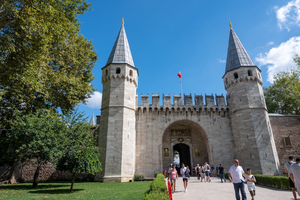 eine Gruppe von Menschen, die außerhalb einer Burg mit dem Topkapı-Palast im Hintergrund spazieren gehen