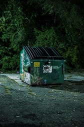 a green garbage can with graffiti on it