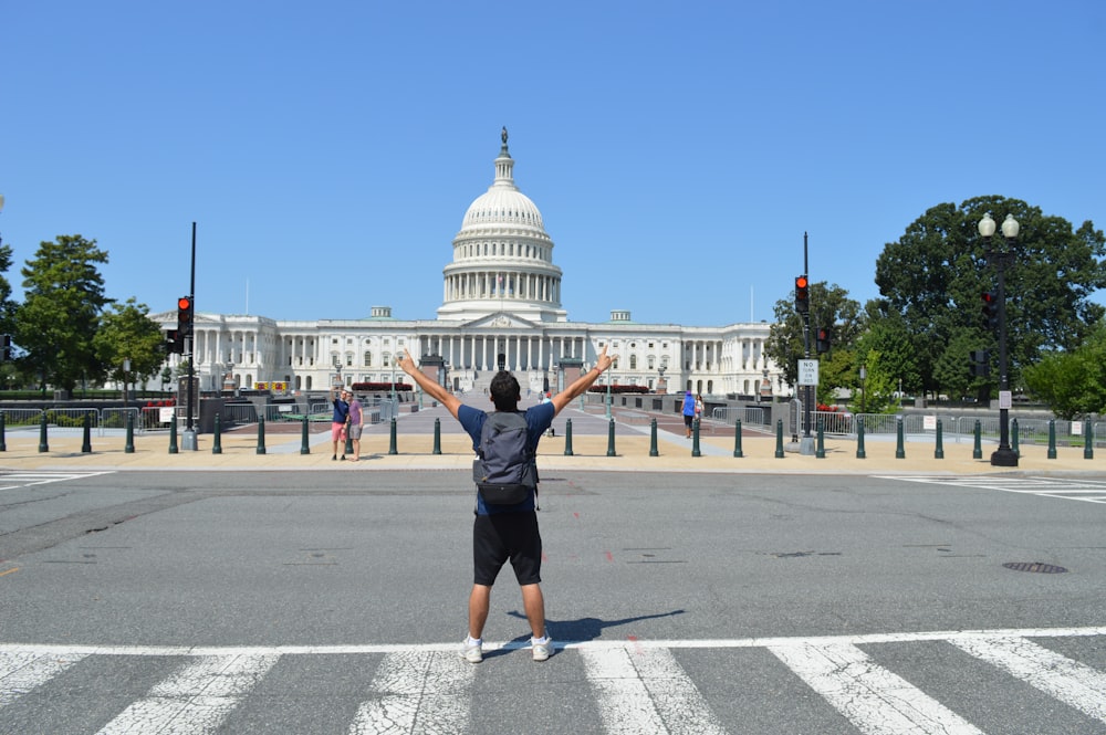 a person standing in a crosswalk in front of a white building