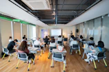a group of people sitting in a room with computers