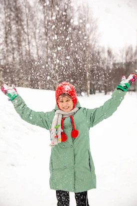 A cheerful person bundled up in a soft, colorful winter jacket standing outdoors on a snowy day.