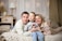 A happy family sitting together in a cozy living room, sharing smiles and laughter.