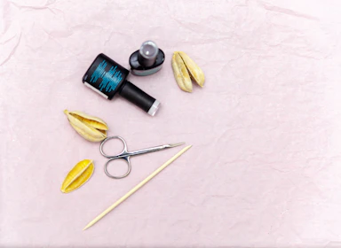 Flat lay of nail art tools and colorful nail tips on a white marble surface.