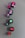 A series of open nail polish bottles are arranged in a diagonal line on a matte surface. The bottles have different shades of polish including pink, purple, green, and red. Shadows cast by the bottles are visible on the surface.