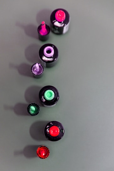 Close-up of vibrant nail polish bottles arranged in a rainbow gradient on a wooden table.