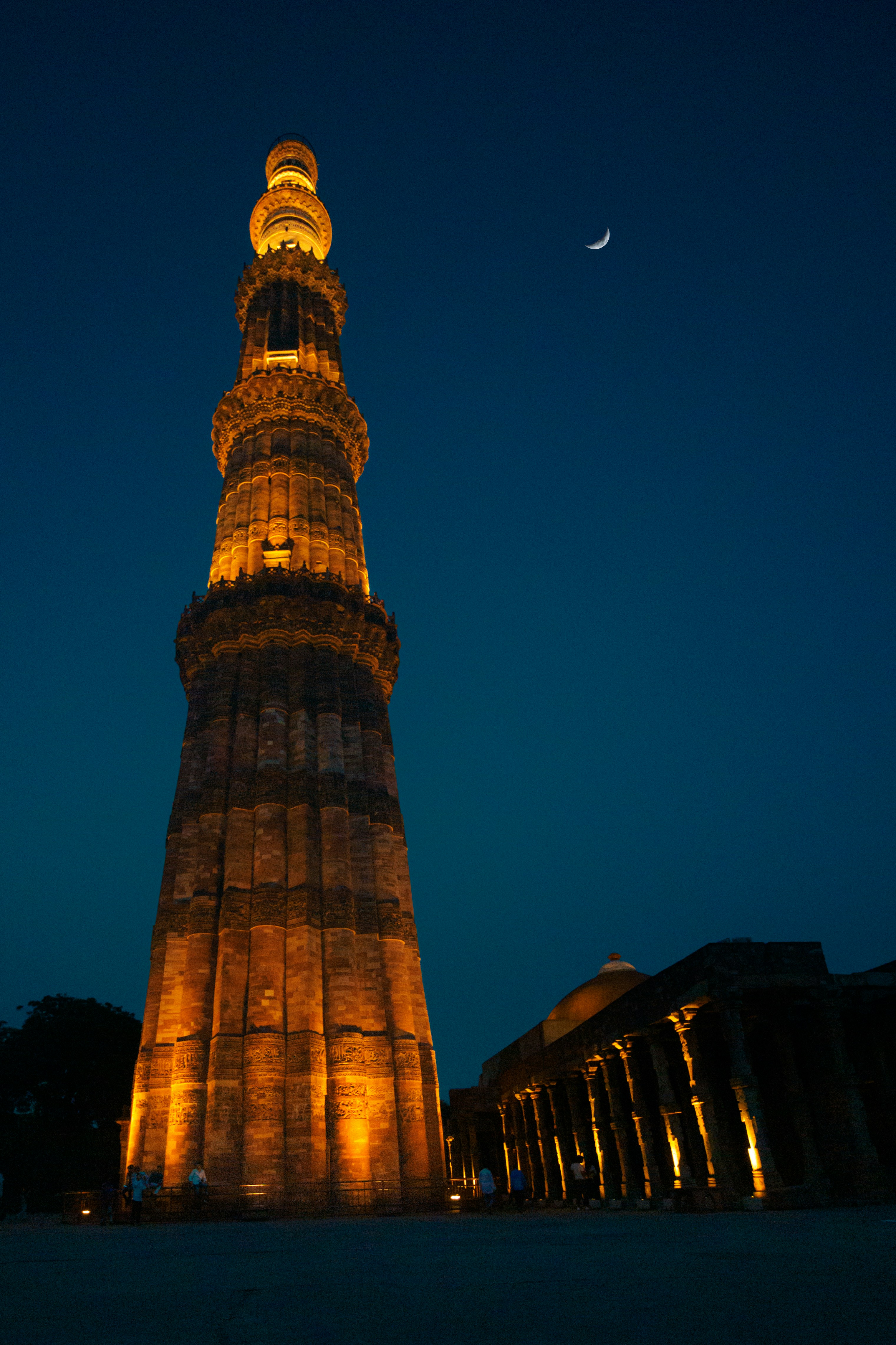 A tall tower with lights at night with qutub minar in the ...