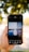 A hand is holding a smartphone displaying an image editing app. The app shows a photo of a building with reflective glass panels and the words 'Your only limit is your mind' overlaid on it. The background is out of focus, featuring greenery and dappled sunlight.