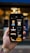 A hand holding a smartphone displaying several fashion and beauty icons. The screen shows images such as a dress, a face with a hat, a comb, a razor, and other beauty-related icons. The background appears out of focus, adding emphasis to the phone's screen.