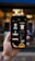 A hand holding a smartphone displaying several fashion and beauty icons. The screen shows images such as a dress, a face with a hat, a comb, a razor, and other beauty-related icons. The background appears out of focus, adding emphasis to the phone's screen.