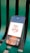 A smartphone displaying an app interface with a design that reads 'Time is Money' alongside a money bag icon. The phone is placed on a green, metal bench with visible slats.