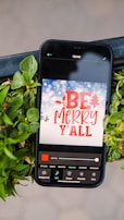A 3D illustration of a smartphone displaying a warning alert about suspicious holiday emails.