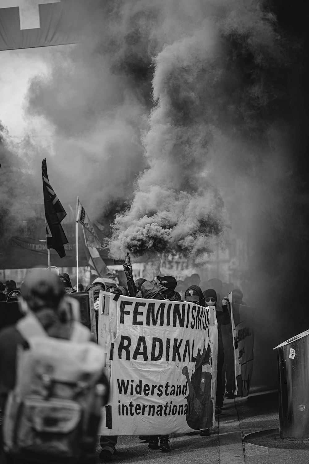 a group of people holding signs and flags with smoke behind them